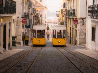 Two yellow trams passing on a narrow cobbled street in Lisbon