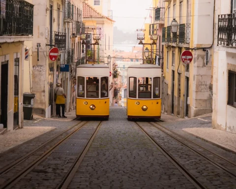 Two yellow trams passing on a narrow cobbled street in Lisbon