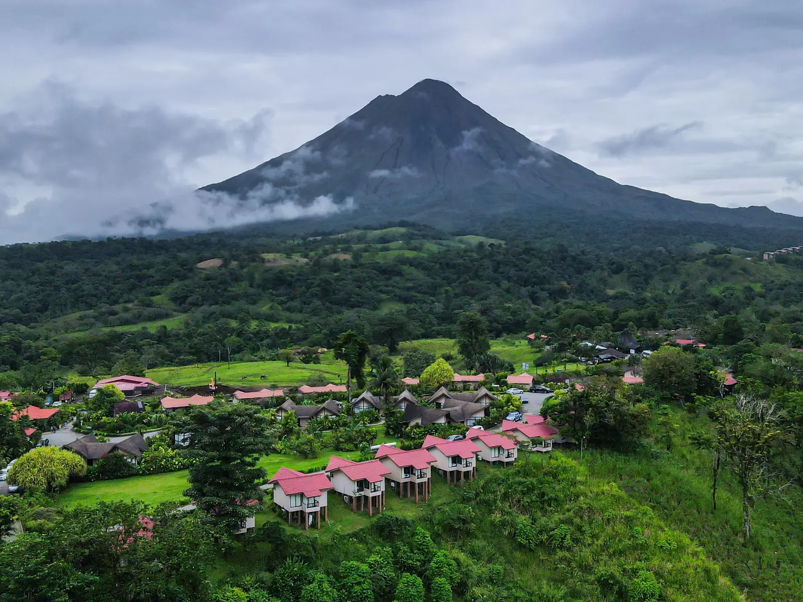 Arenal Volcano rising above the green hills and rooftops of La Fortuna
