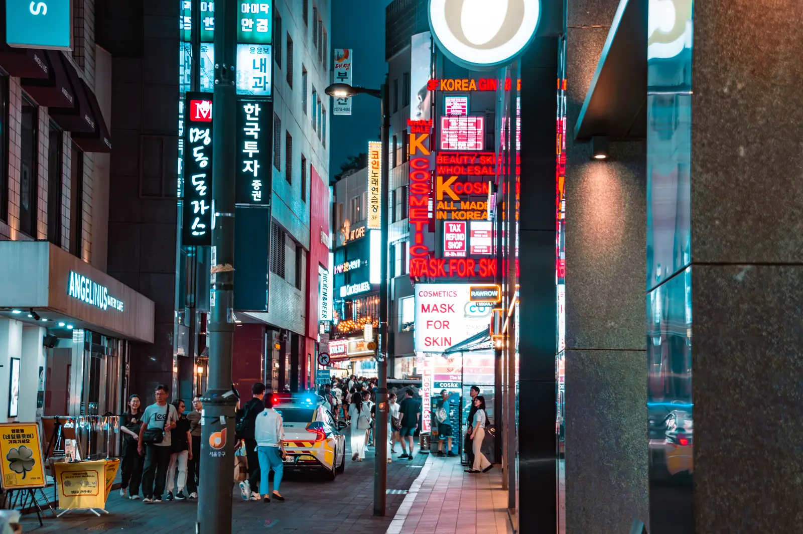 A neon lit shopping street busy with people at night in Seoul