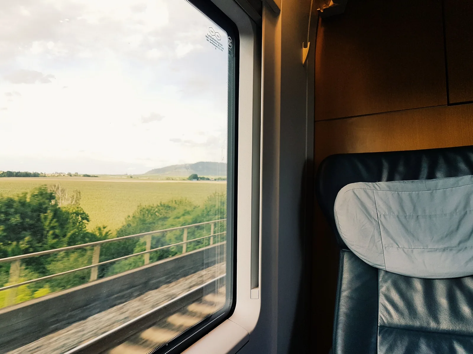 A view of green countryside through the window of a moving train