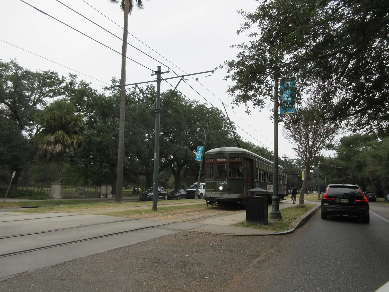 A green St. Charles Avenue streetcar stopped under live oaks in uptown New Orleans