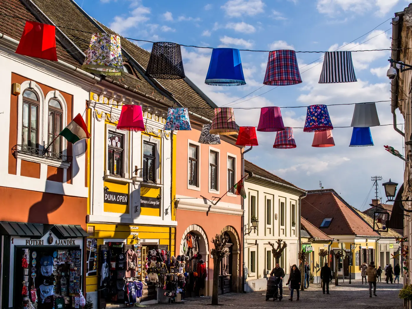 Colourful lampshades strung above a street of pastel houses in Szentendre