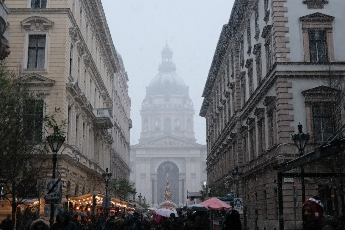 Snow falling over a Budapest street with the Christmas market and St. Stephen's Basilica ahead