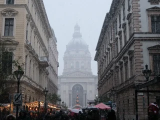 Snow falling over a Budapest street with the Christmas market and St. Stephen's Basilica ahead