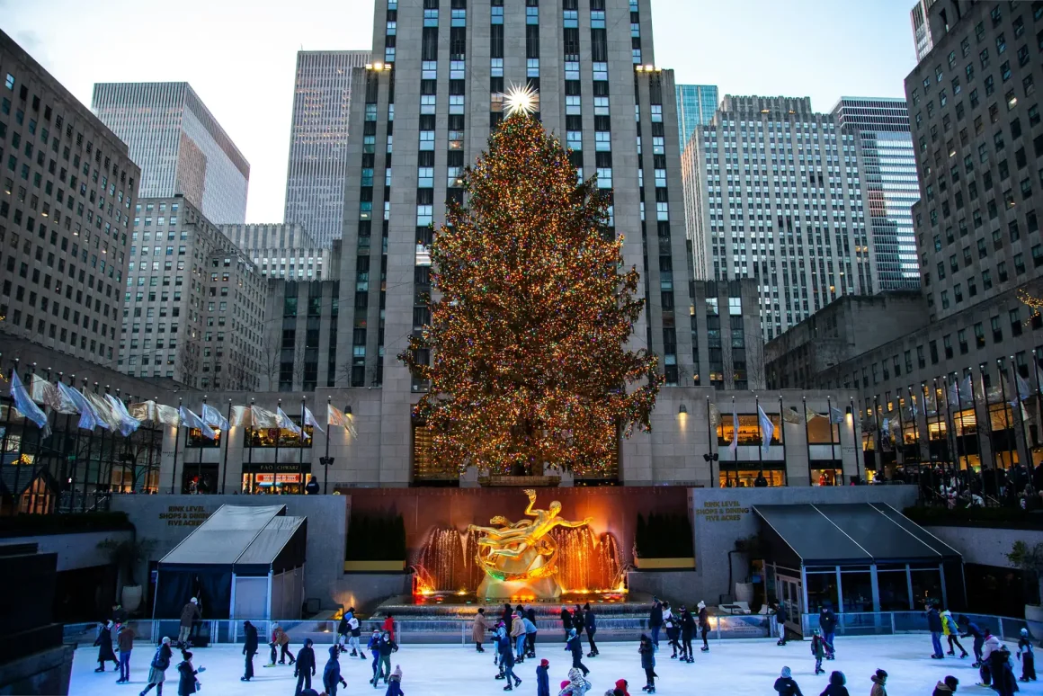 The Rockefeller Center Christmas tree lit above the ice rink with skaters below