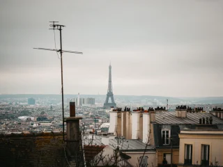 Paris rooftops and chimney pots under a soft grey winter sky with the Eiffel Tower in the distance