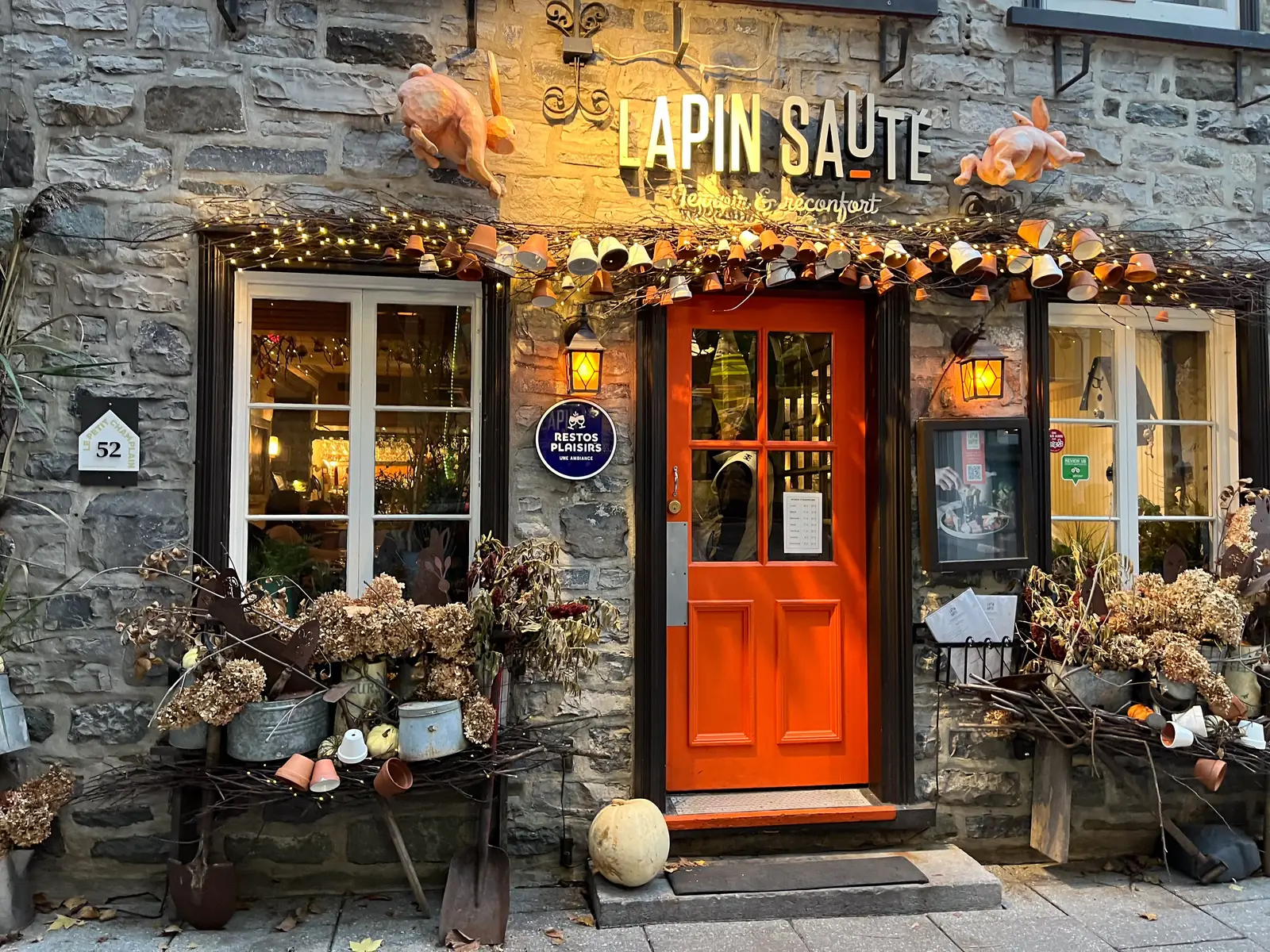 The front of a restaurant in Old Quebec lit up at dusk