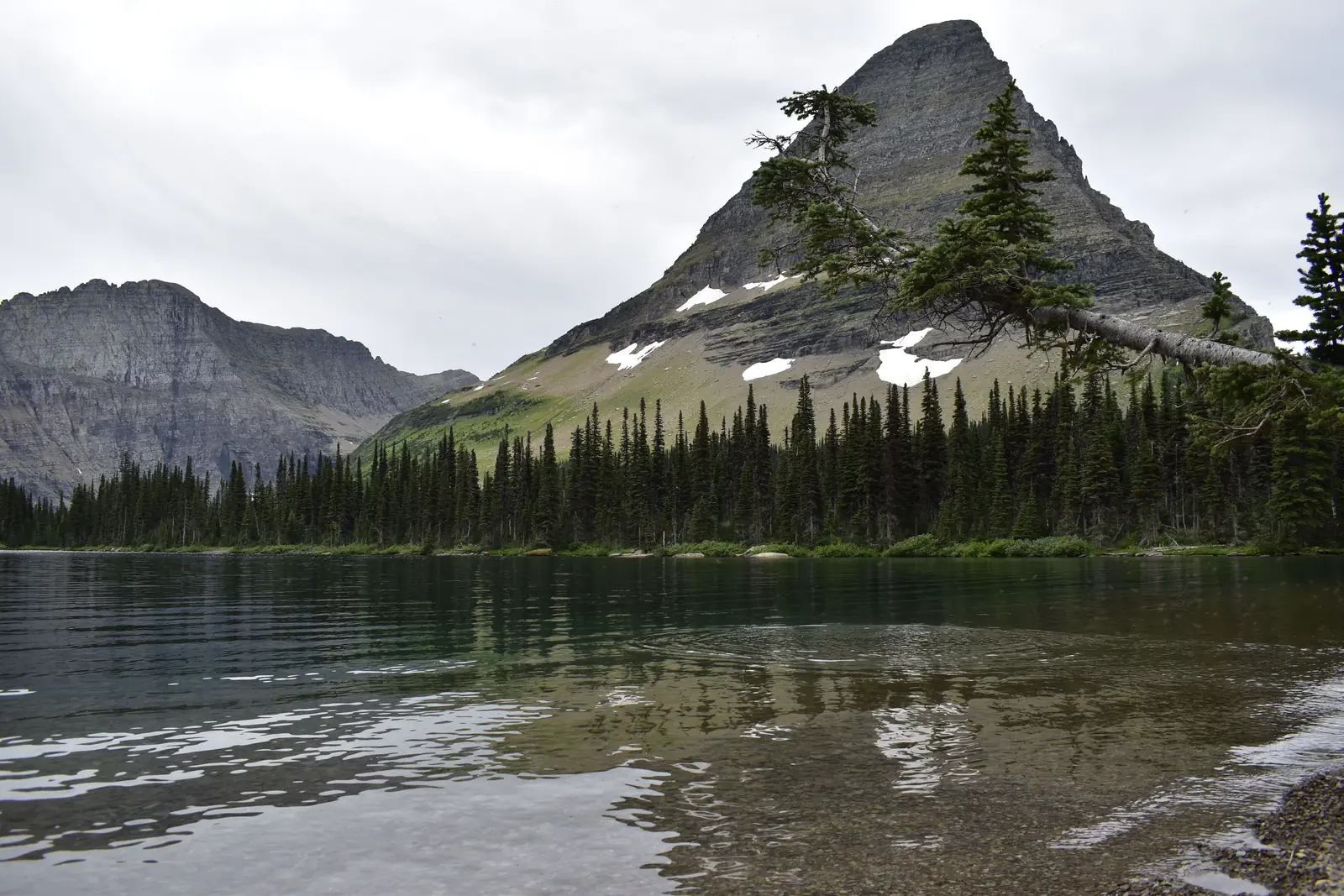A pyramid shaped peak rising above the still water of Two Medicine Lake