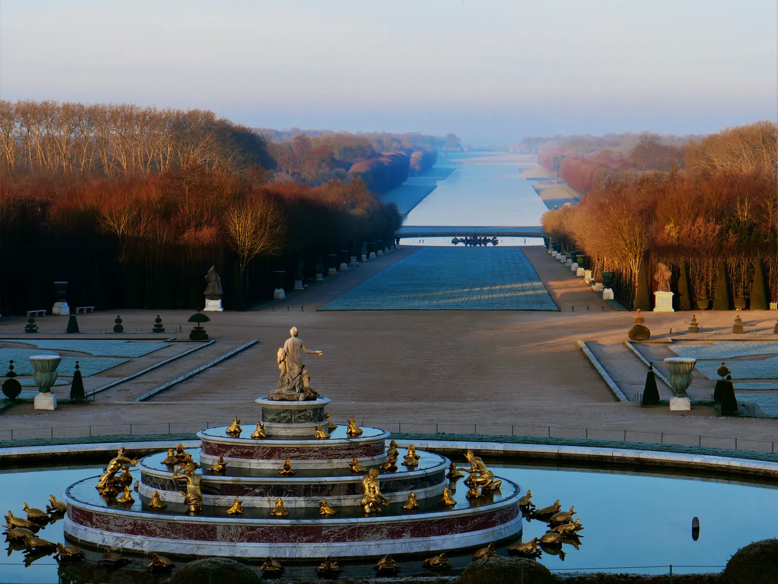A golden fountain and autumn trees in the gardens of Versailles
