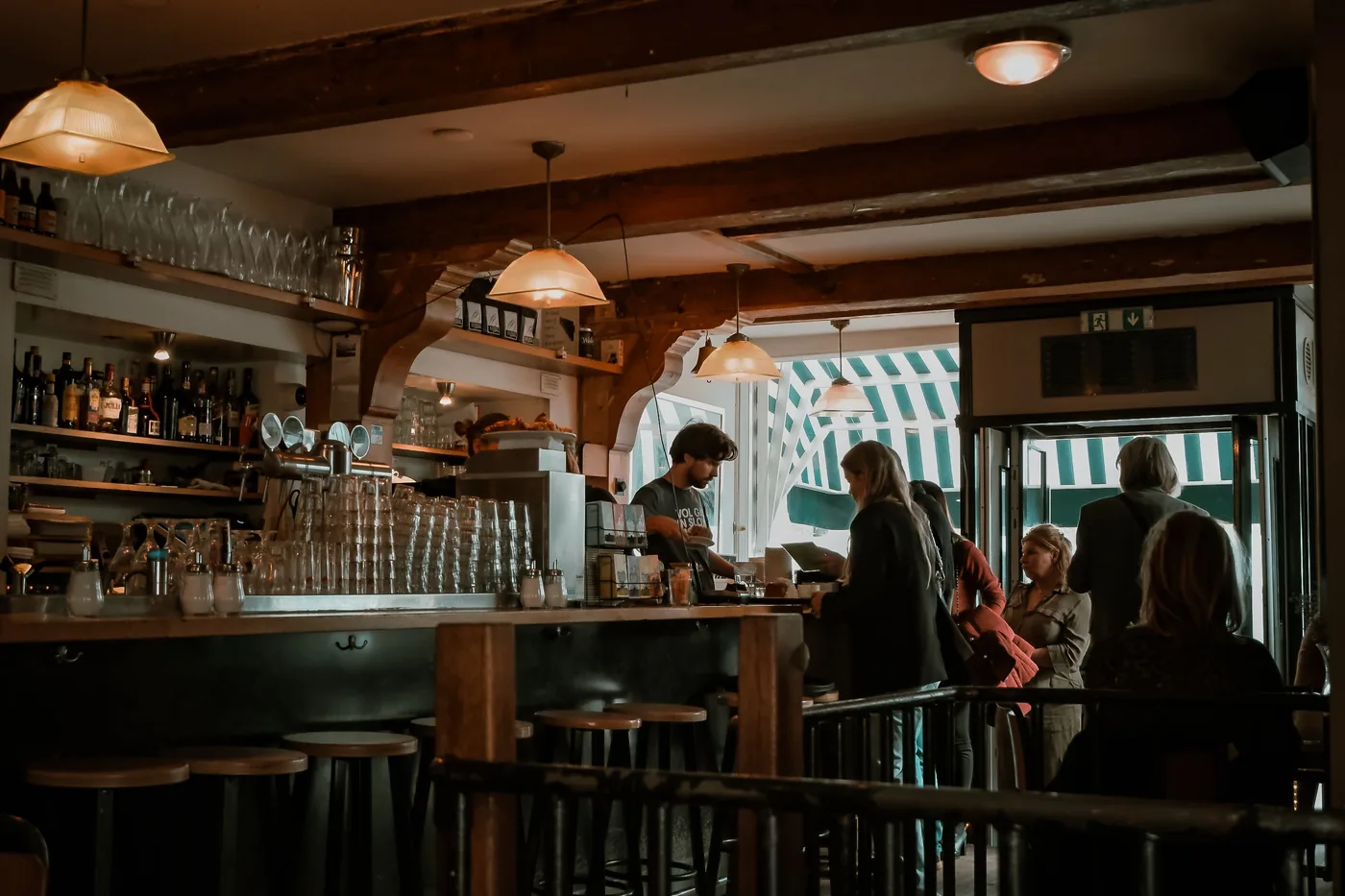 The dark wood bar and hanging lamps inside a traditional Amsterdam brown cafe