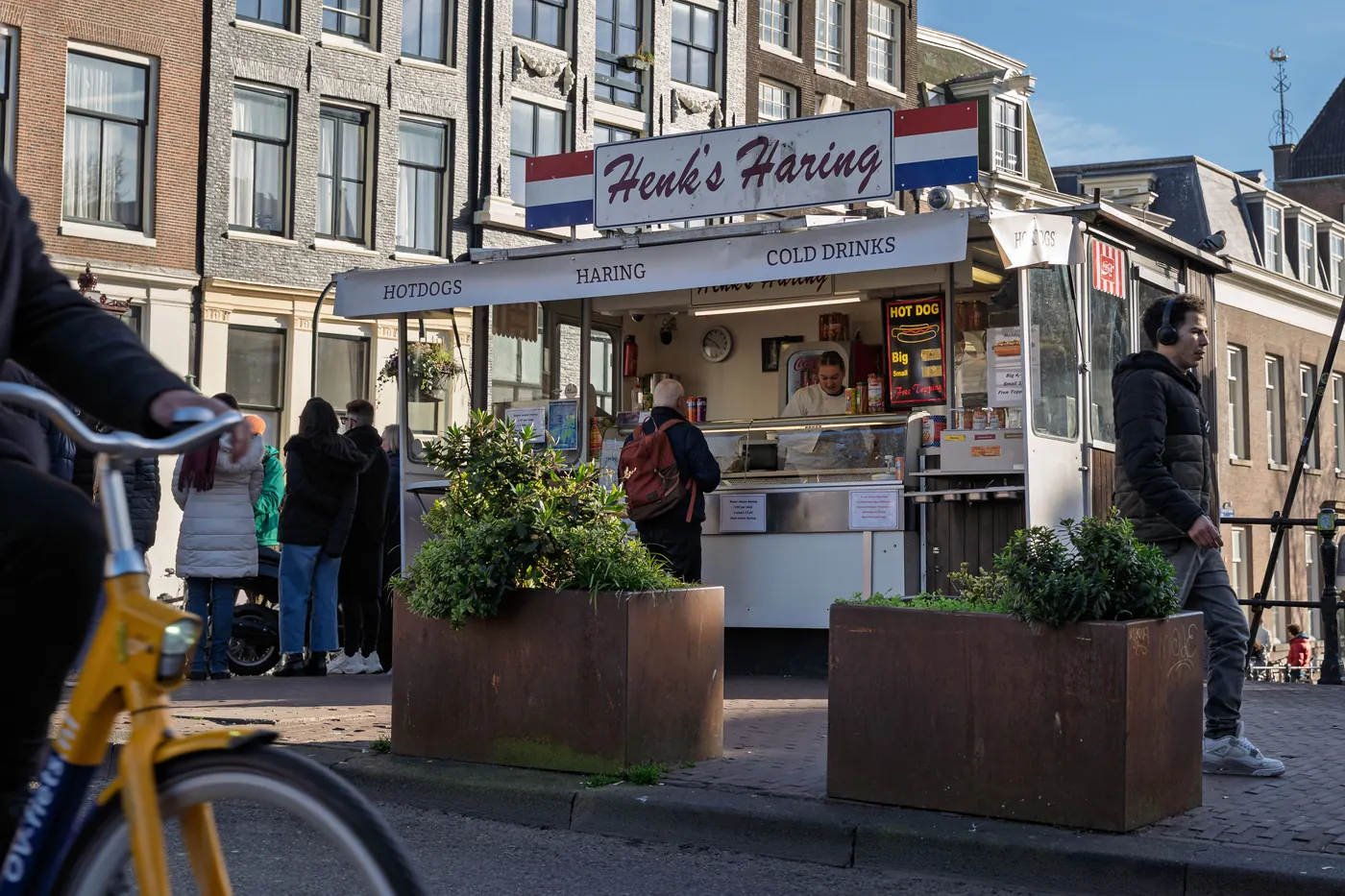 People in winter coats queuing at a Dutch herring stand on an Amsterdam street