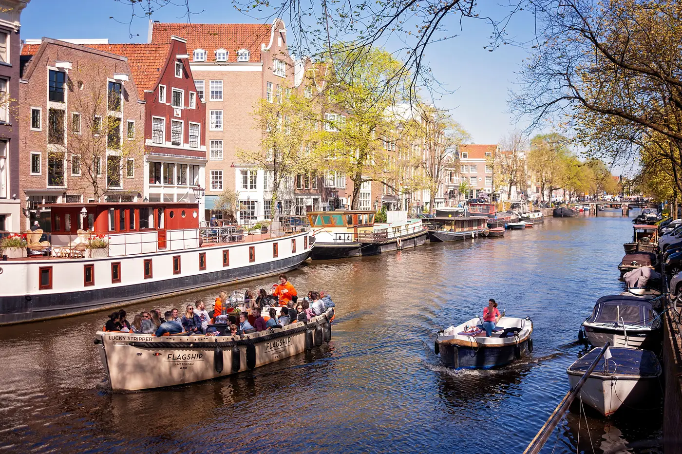 An open tour boat full of people on an Amsterdam canal