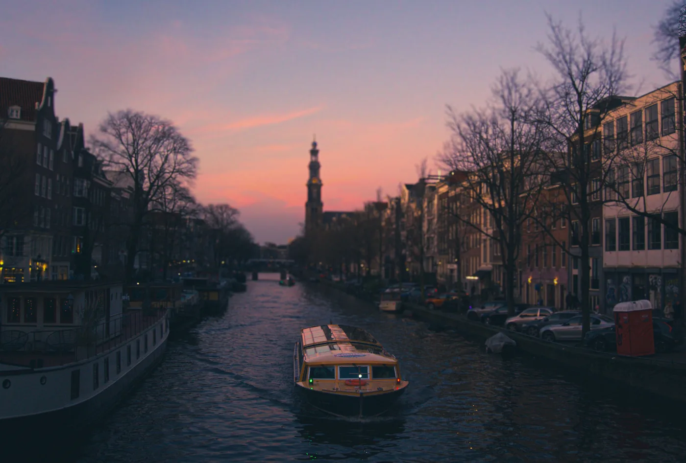 The Westerkerk tower above an Amsterdam canal at sunset