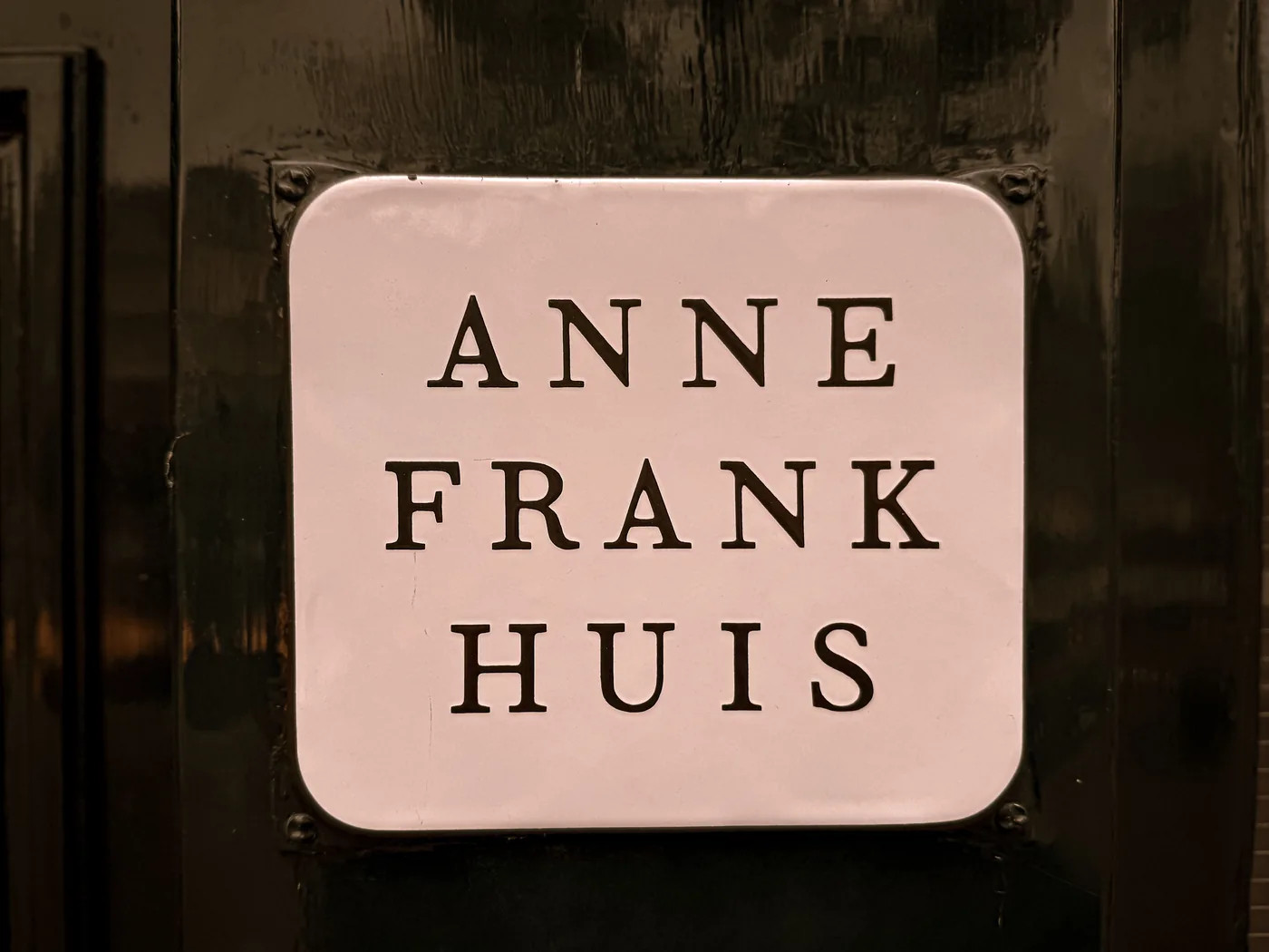 The Anne Frank Huis nameplate mounted on the dark door of the house in Amsterdam