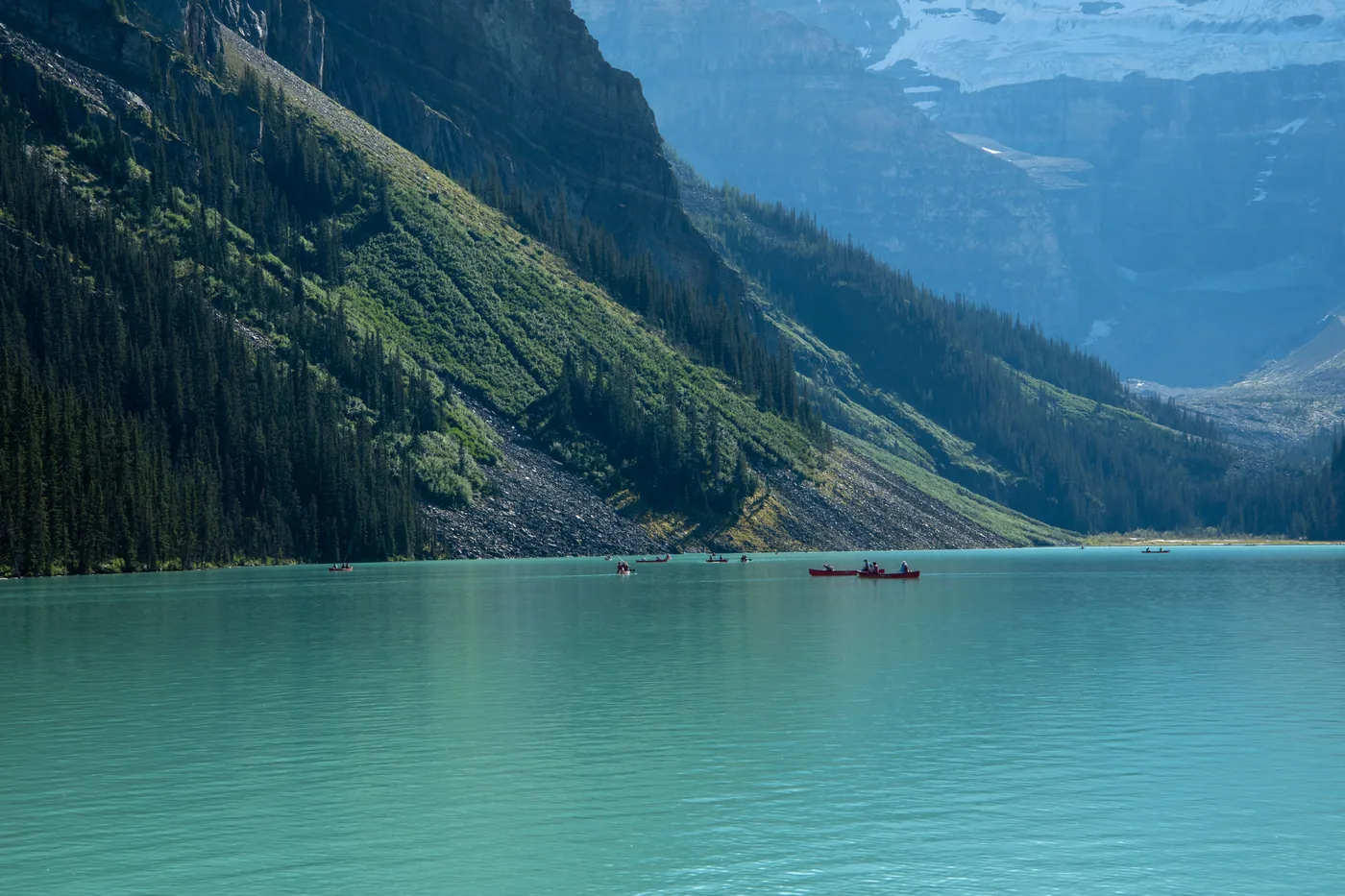 Canoes on the turquoise water of Lake Louise below the mountains in Banff