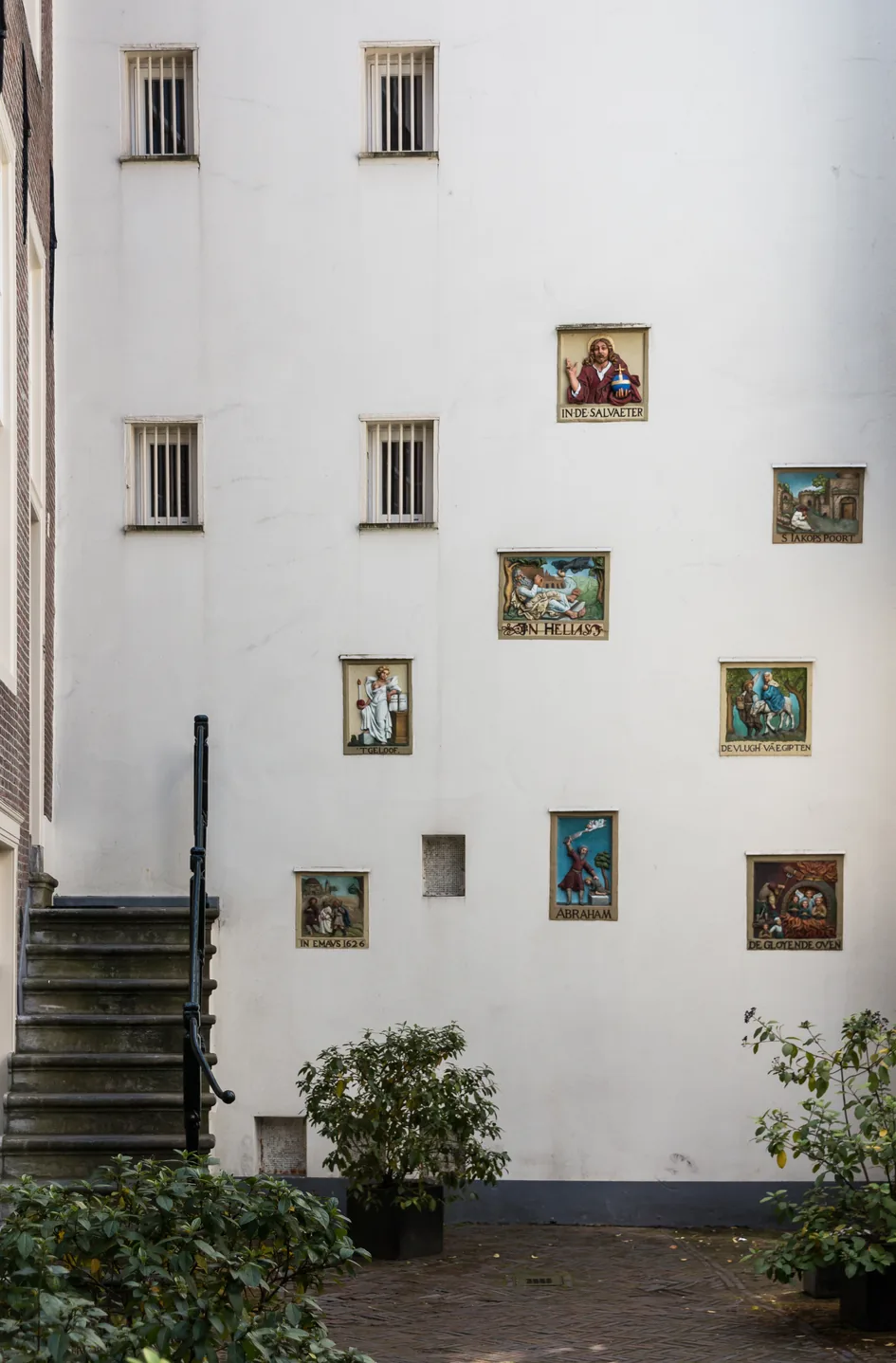 Painted gable stones set into a white wall in the Begijnhof courtyard in Amsterdam