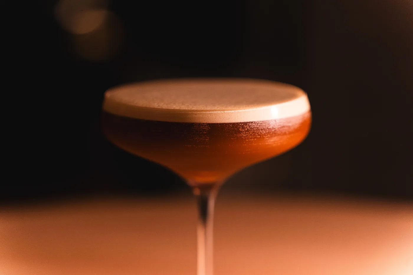 A cocktail on the bar in a dimly lit lounge