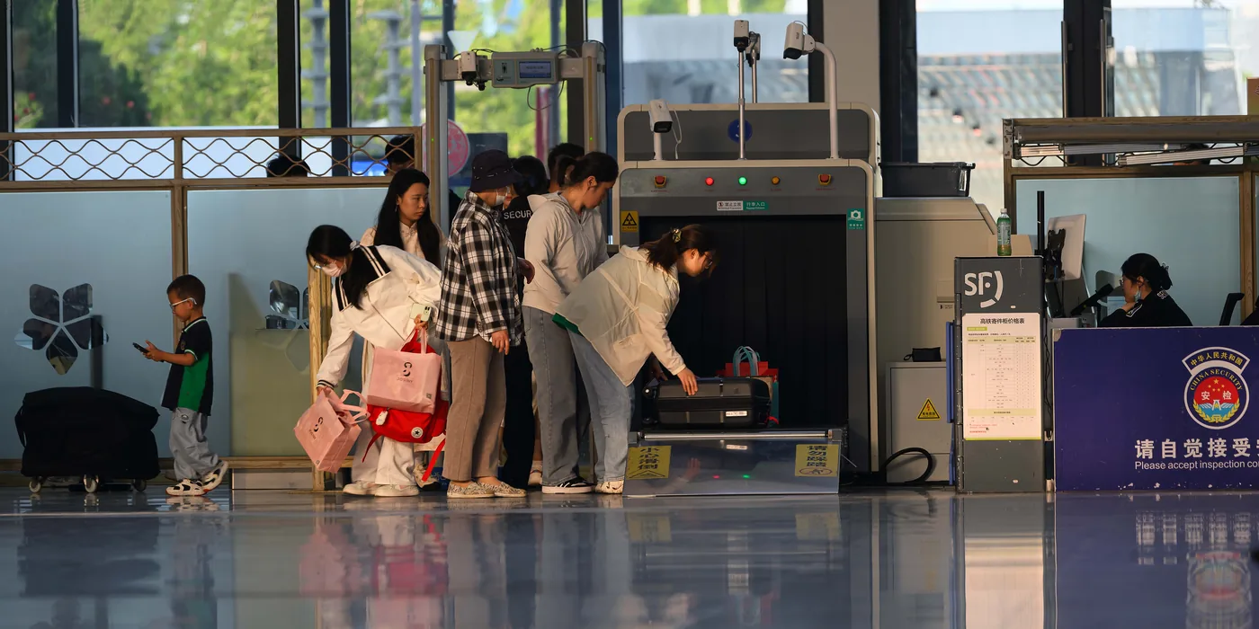 Travelers putting their bags through an airport security scanner