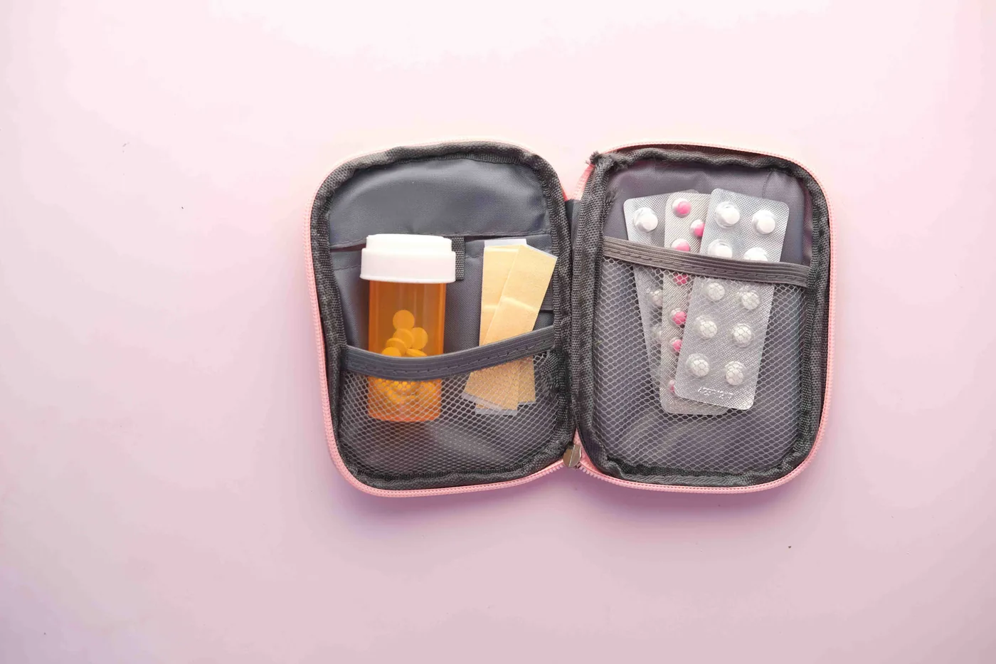A zip travel pouch holding a prescription bottle and blister packs of pills