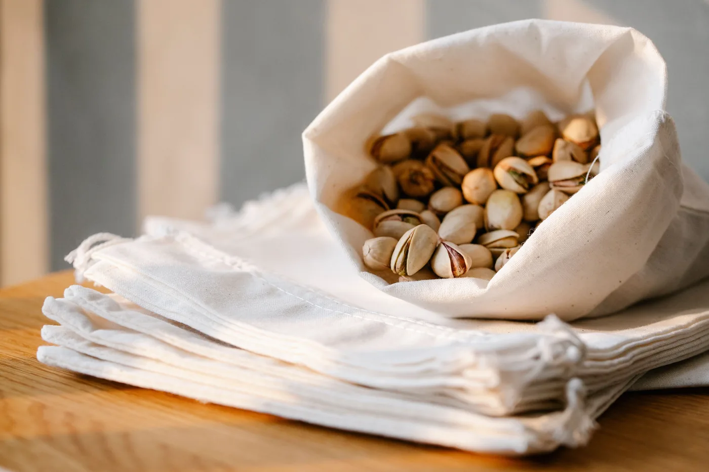A cloth bag full of pistachios on a wooden table