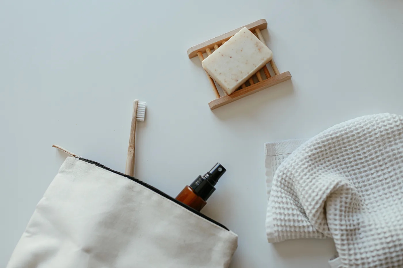 A canvas toiletry bag with a toothbrush, spray bottle, soap and a small towel