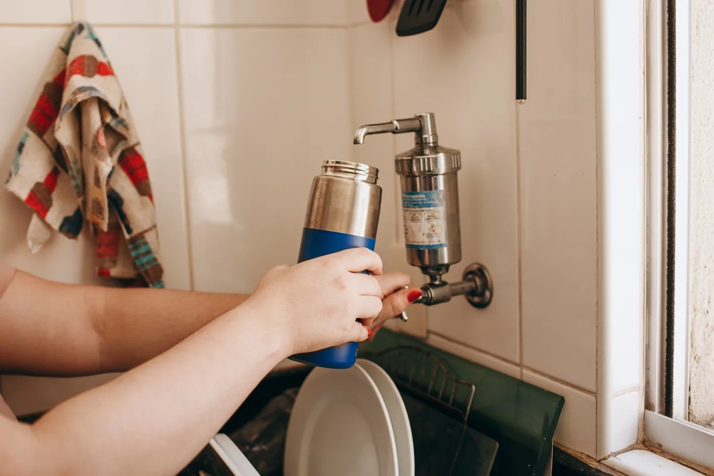 Filling a reusable steel water bottle at a tap