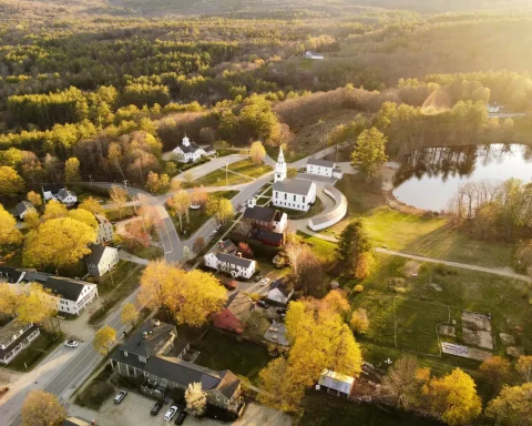 An aerial view of a small town with a white church in autumn