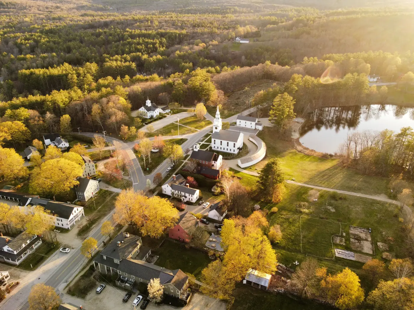 An aerial view of a small town with a white church in autumn