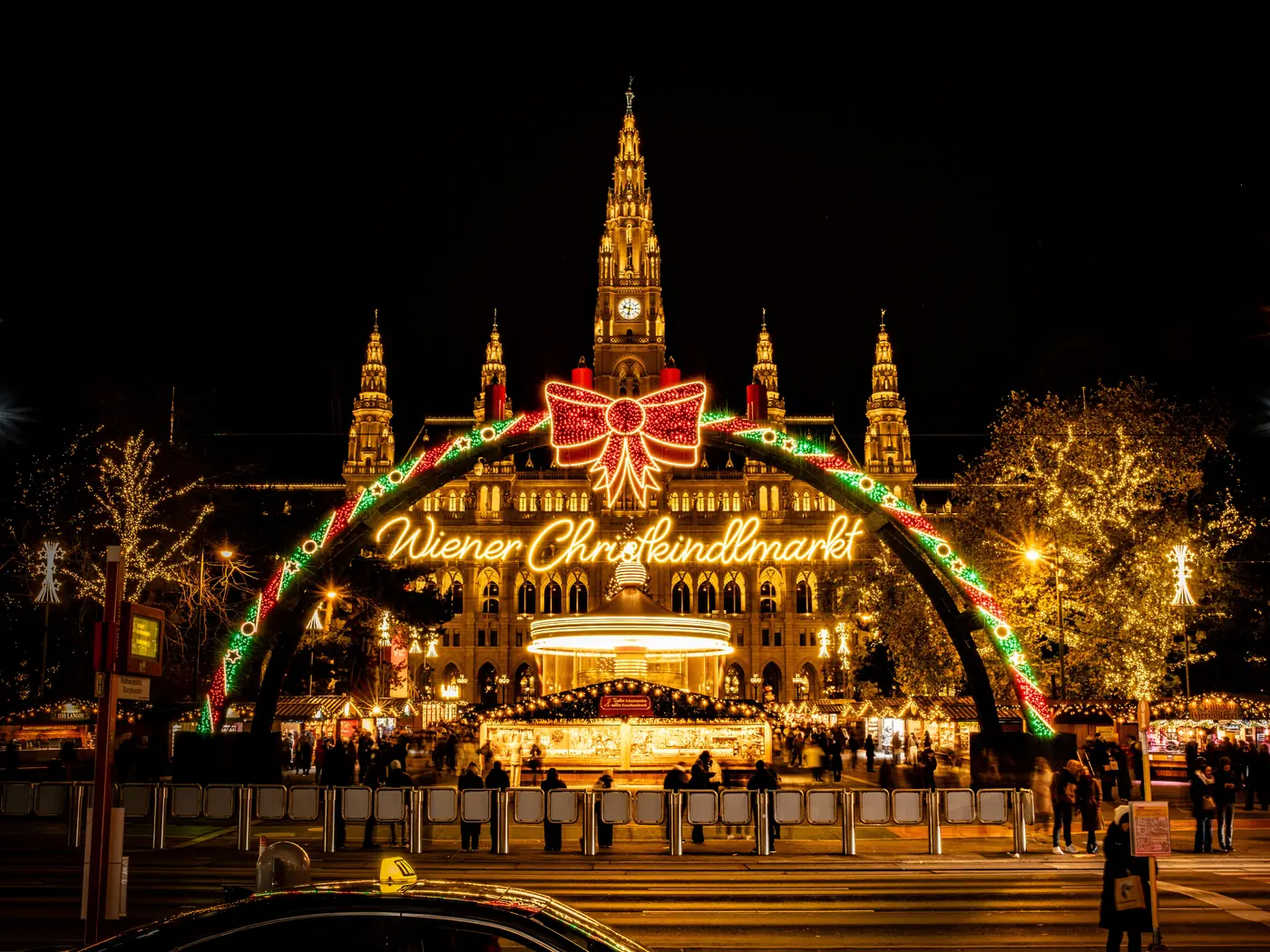 The Wiener Christkindlmarkt arch glowing in front of Vienna City Hall at night