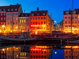 Colorful houses and boats along Nyhavn in Copenhagen in the evening