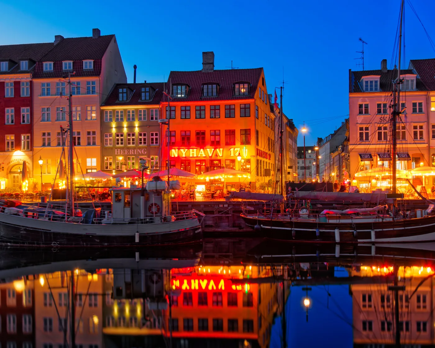 Colorful houses and boats along Nyhavn in Copenhagen in the evening