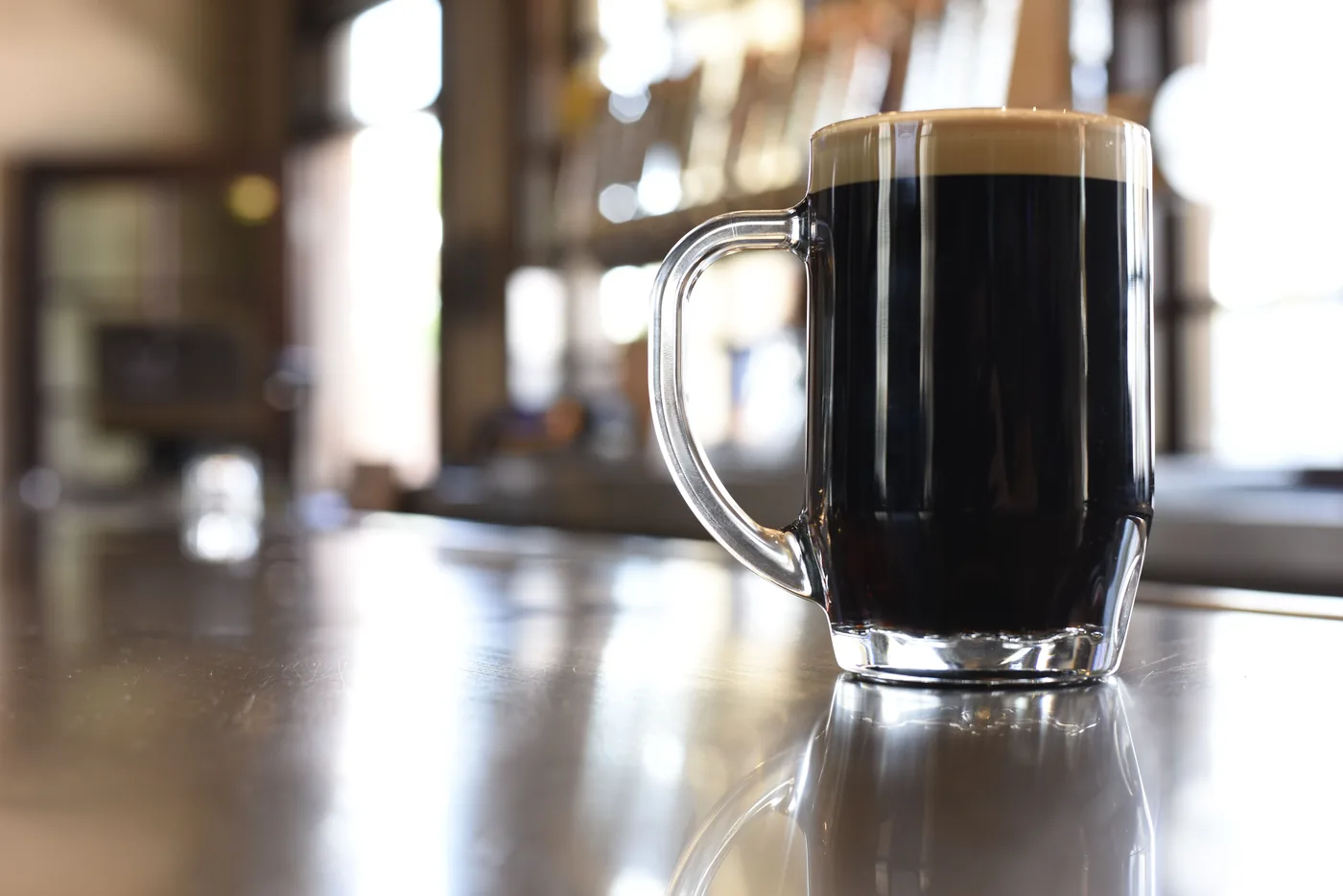 A mug of dark lager on a wooden table
