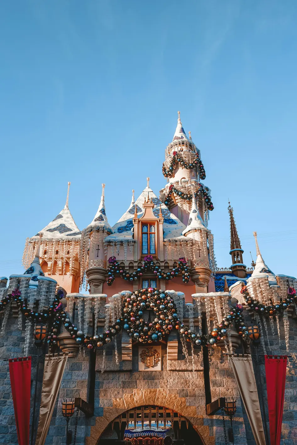 Sleeping Beauty's Winter Castle at Disneyland decorated with snow covered turrets, wreaths and holiday lights