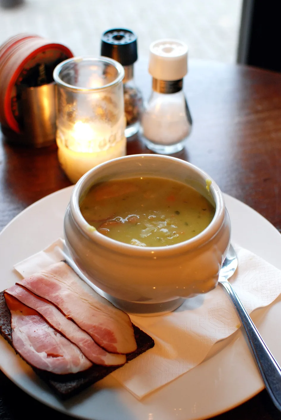 A bowl of Dutch erwtensoep served with rye bread and smoked bacon