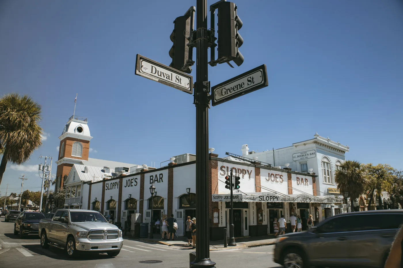 The Duval Street sign at a corner in Key West with bars behind it