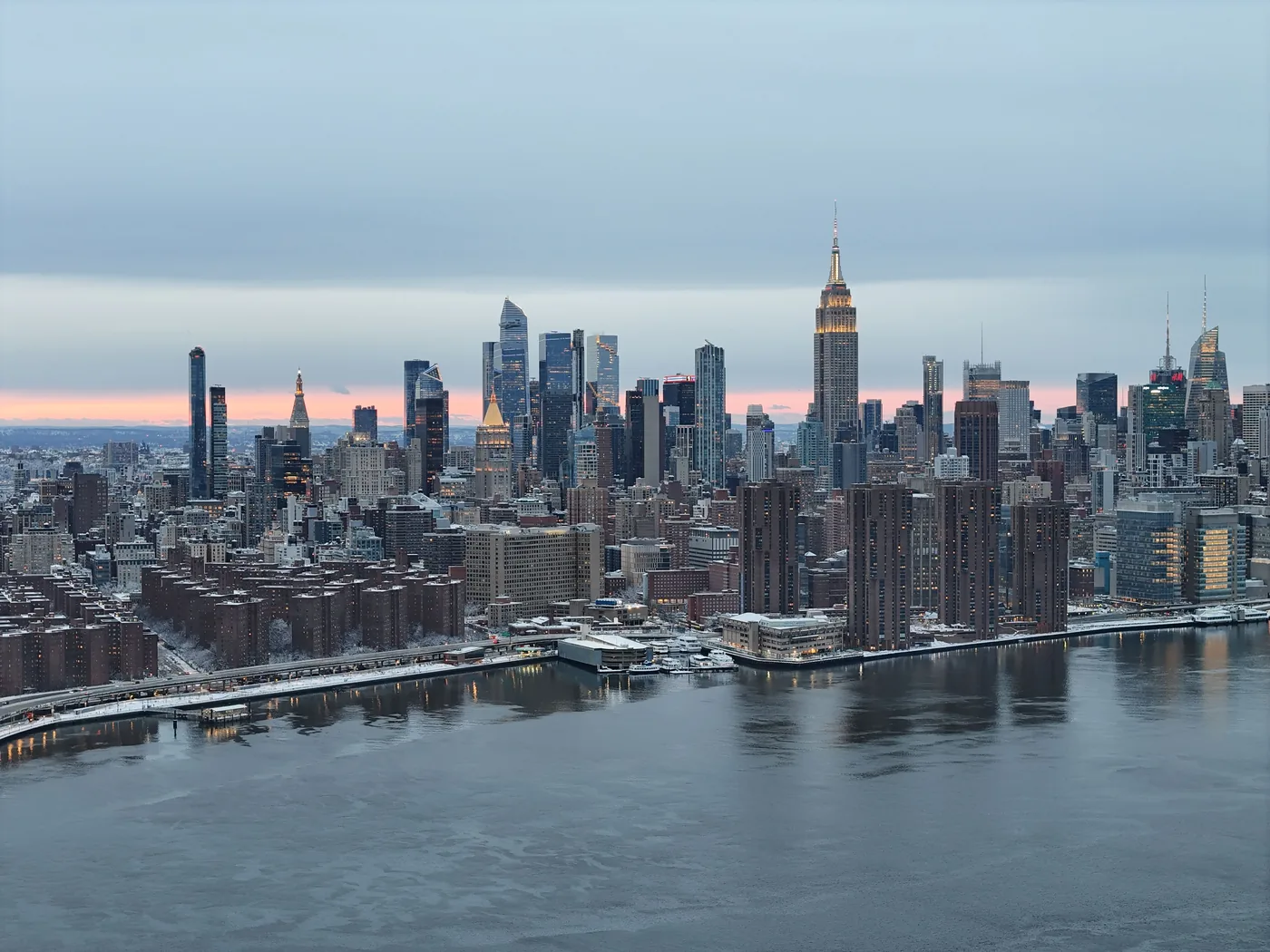The Empire State Building above a snowy Midtown skyline at dusk