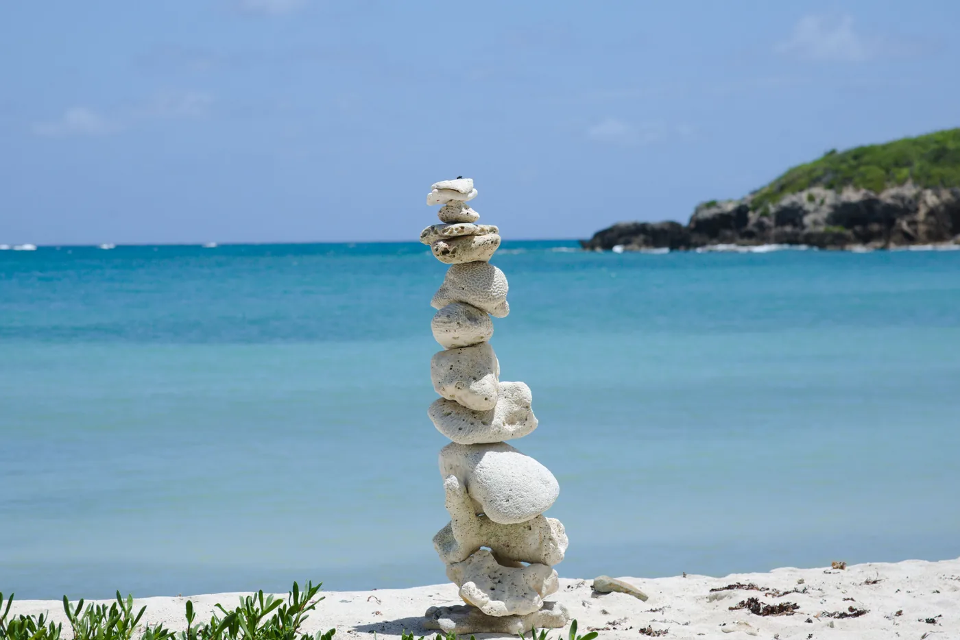 A stacked rock cairn on an empty turquoise beach on Vieques, Puerto Rico