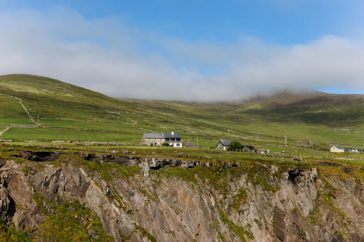 Green fields and cottages above sea cliffs on the Irish coast