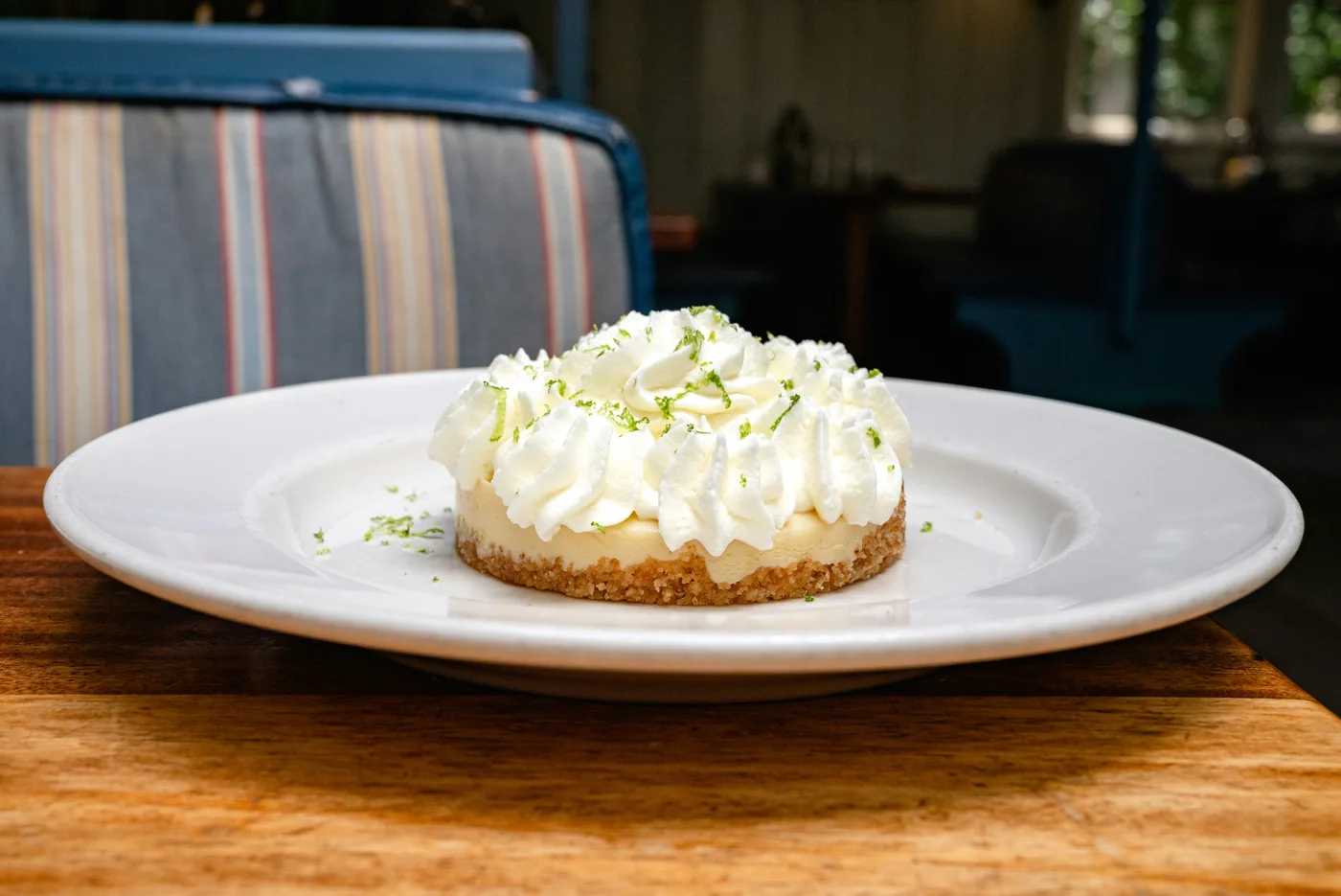 A slice of key lime pie topped with whipped cream and lime zest