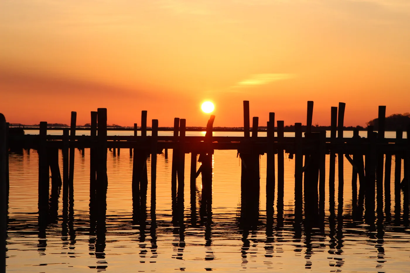 Sunrise over a wooden pier with calm water