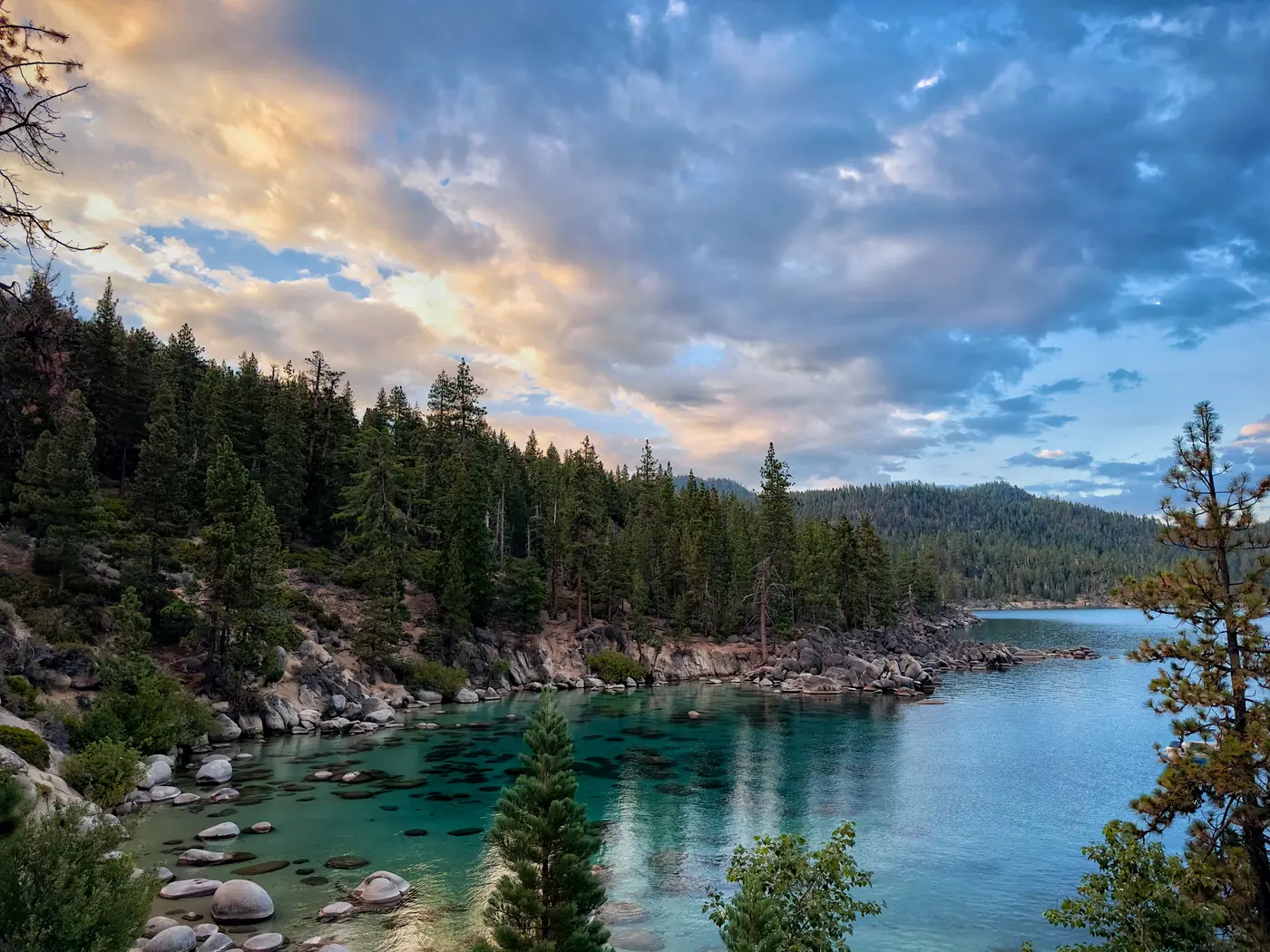 The shoreline of Lake Tahoe at sunset with mountains behind