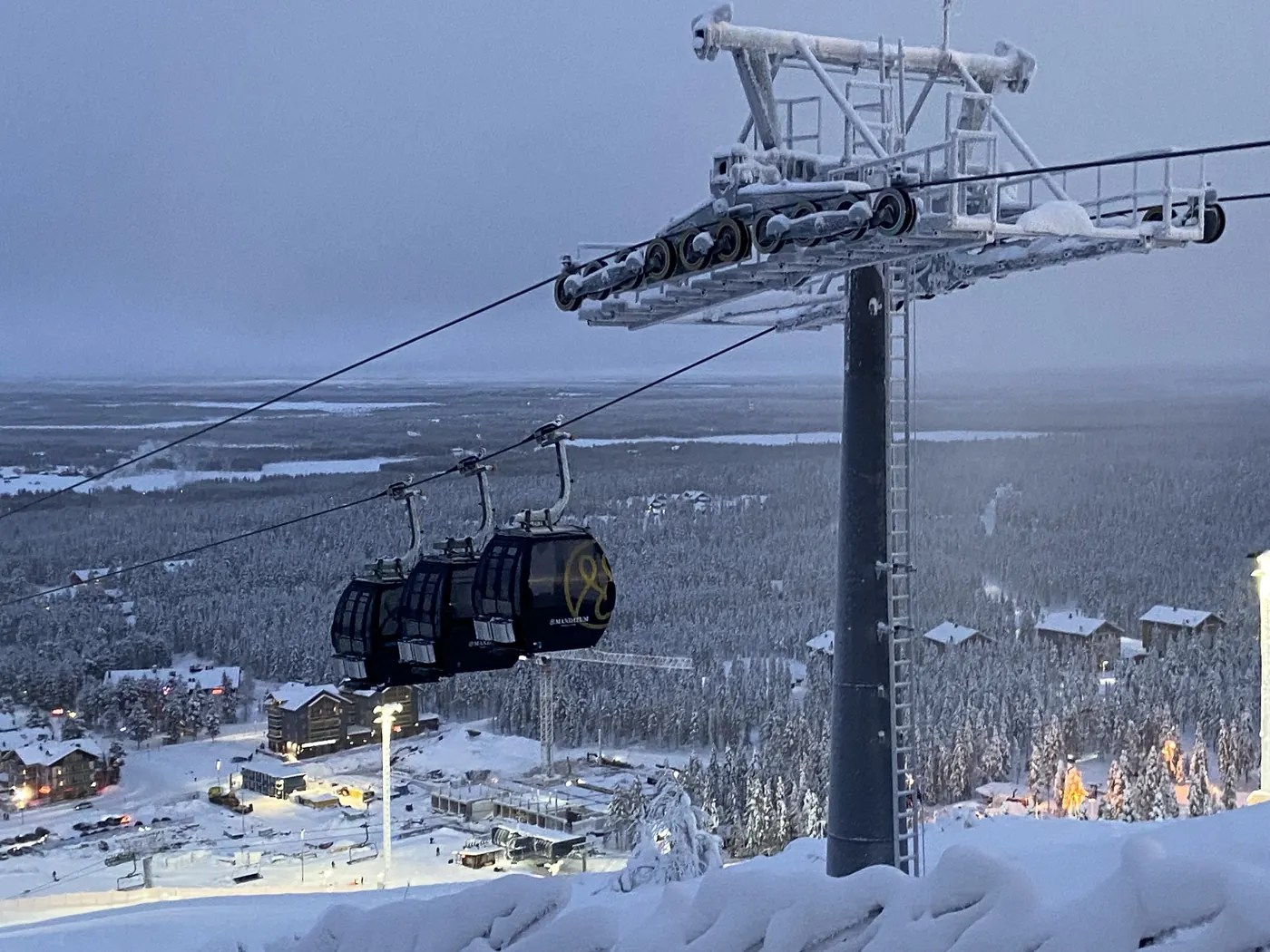 A gondola above the snowy slopes and village of Levi, Finland