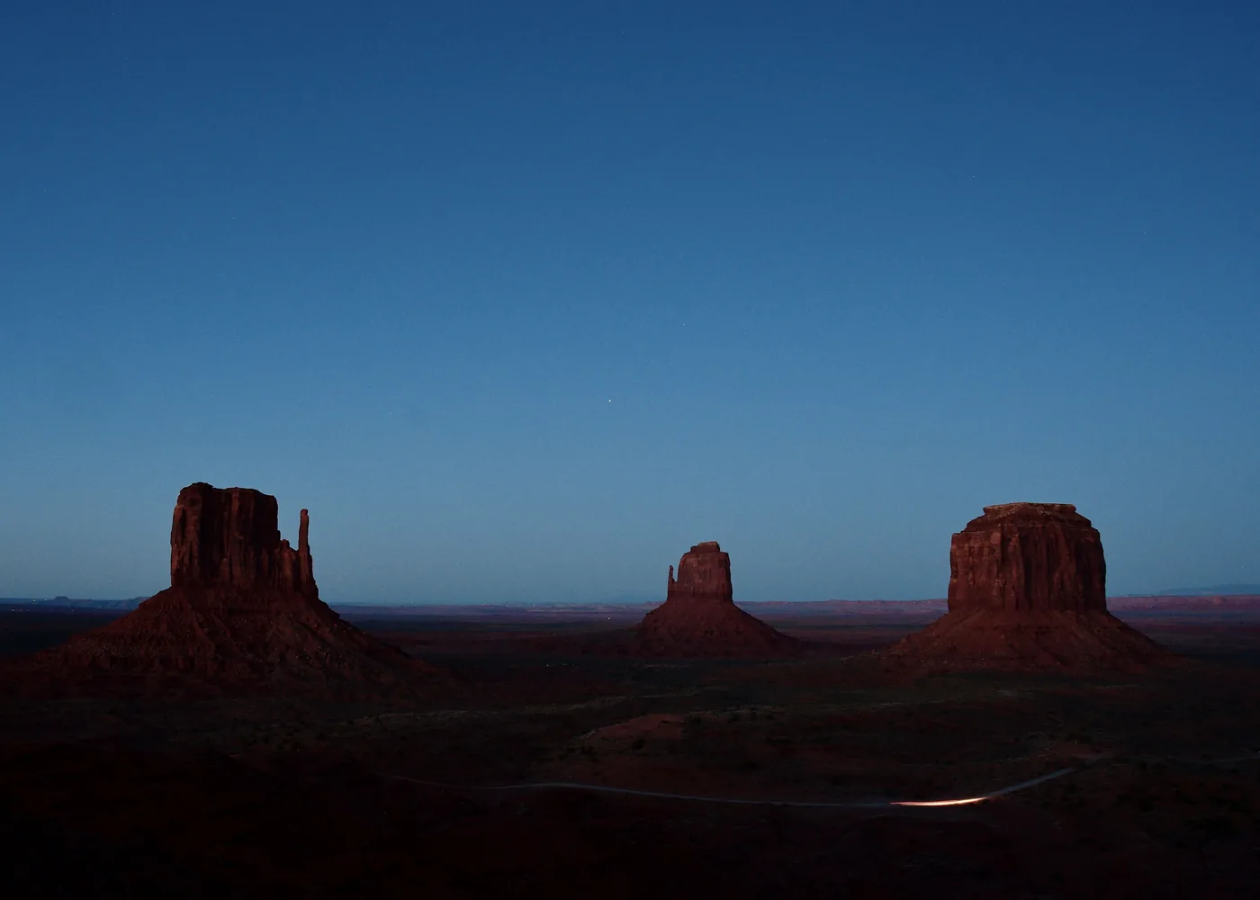 The buttes of Monument Valley at dusk under a deep blue sky