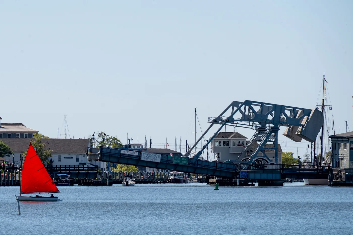 The Mystic River drawbridge with a red sailboat in front