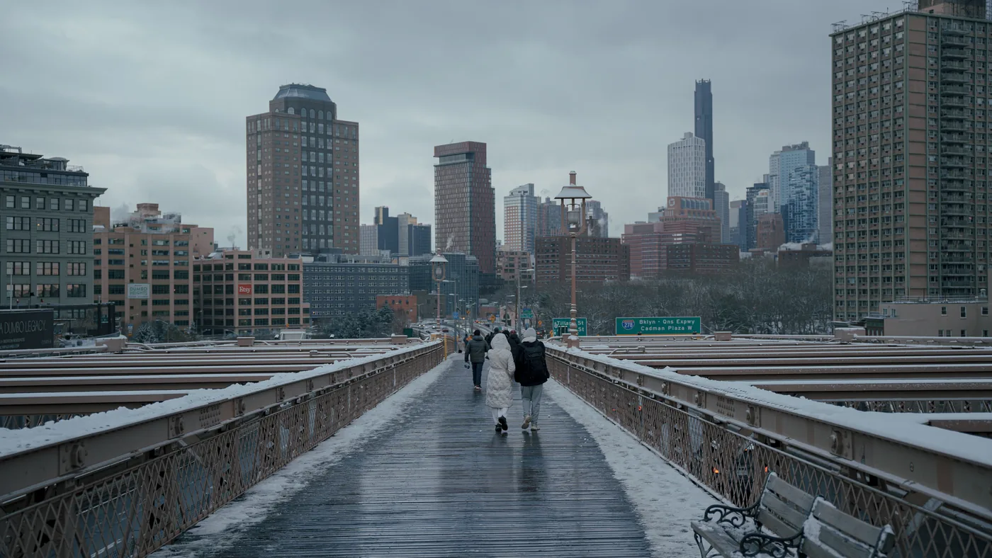 People walking across a snowy Brooklyn Bridge