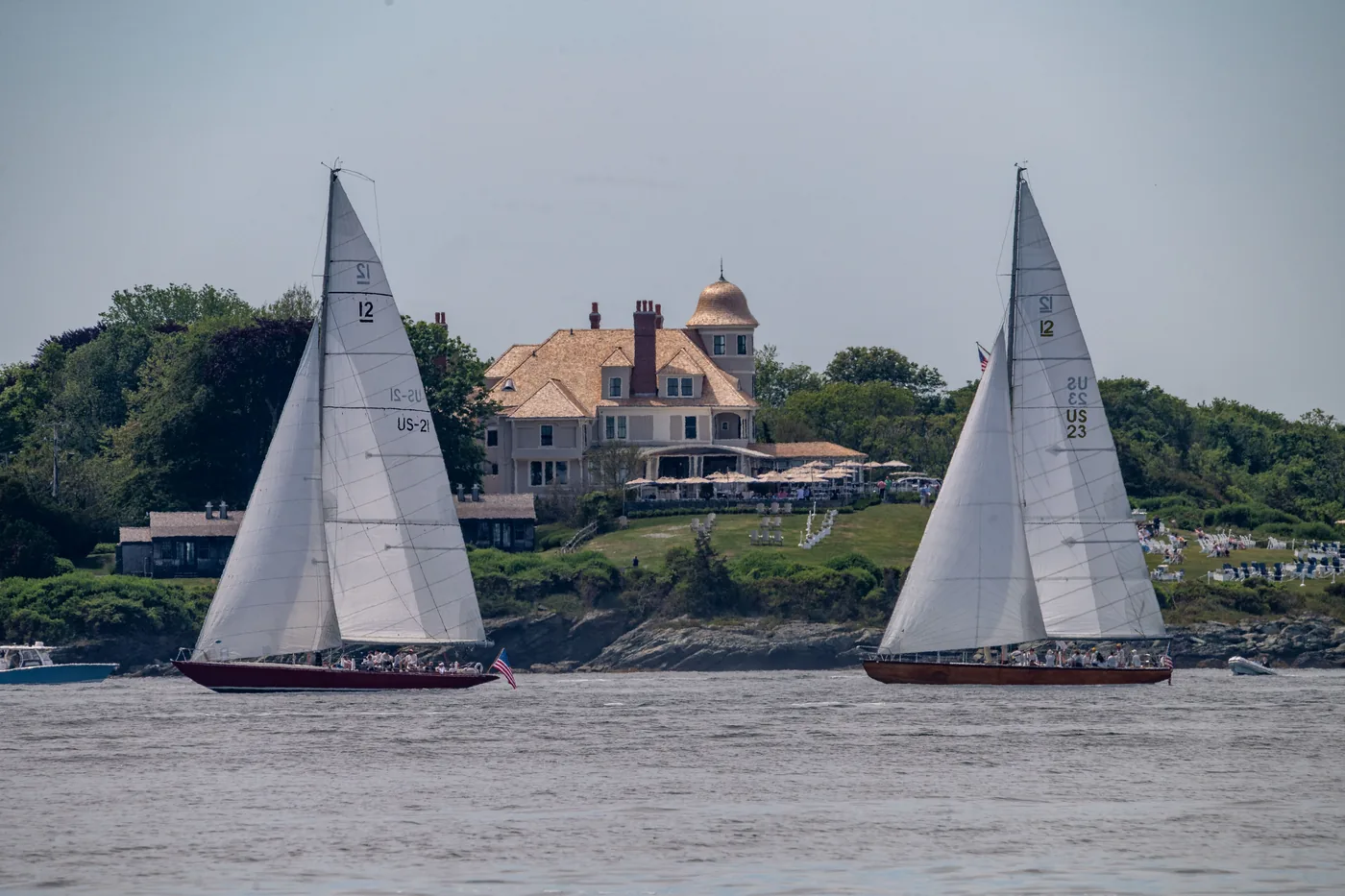 Sailboats passing a mansion on the shore in Newport, Rhode Island