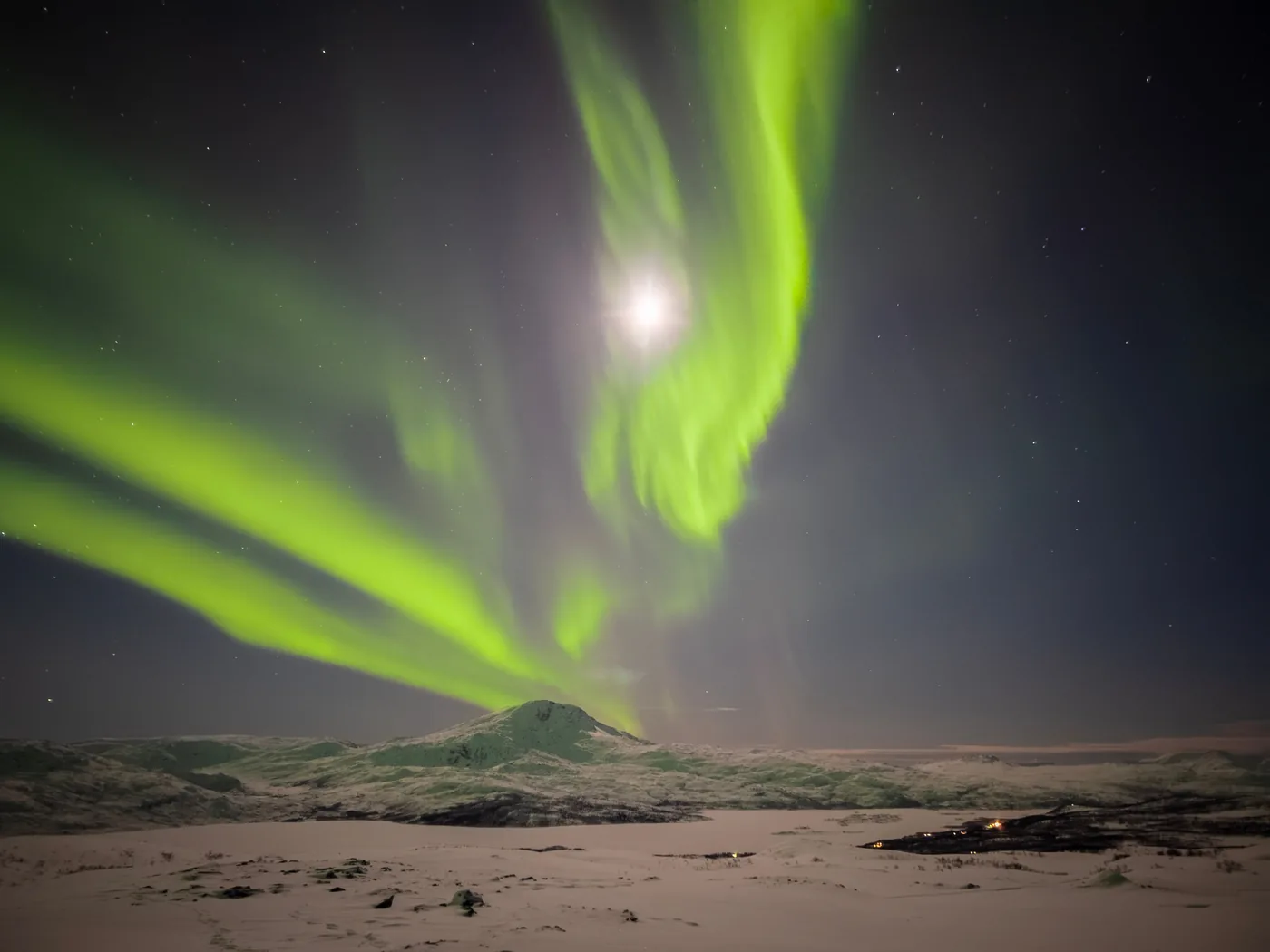 The northern lights over a snowy landscape in Troms, Norway