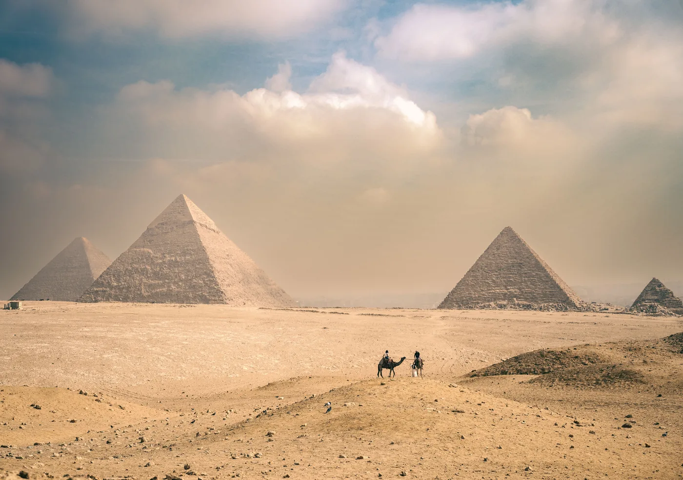 The Pyramids of Giza with camels crossing the sand