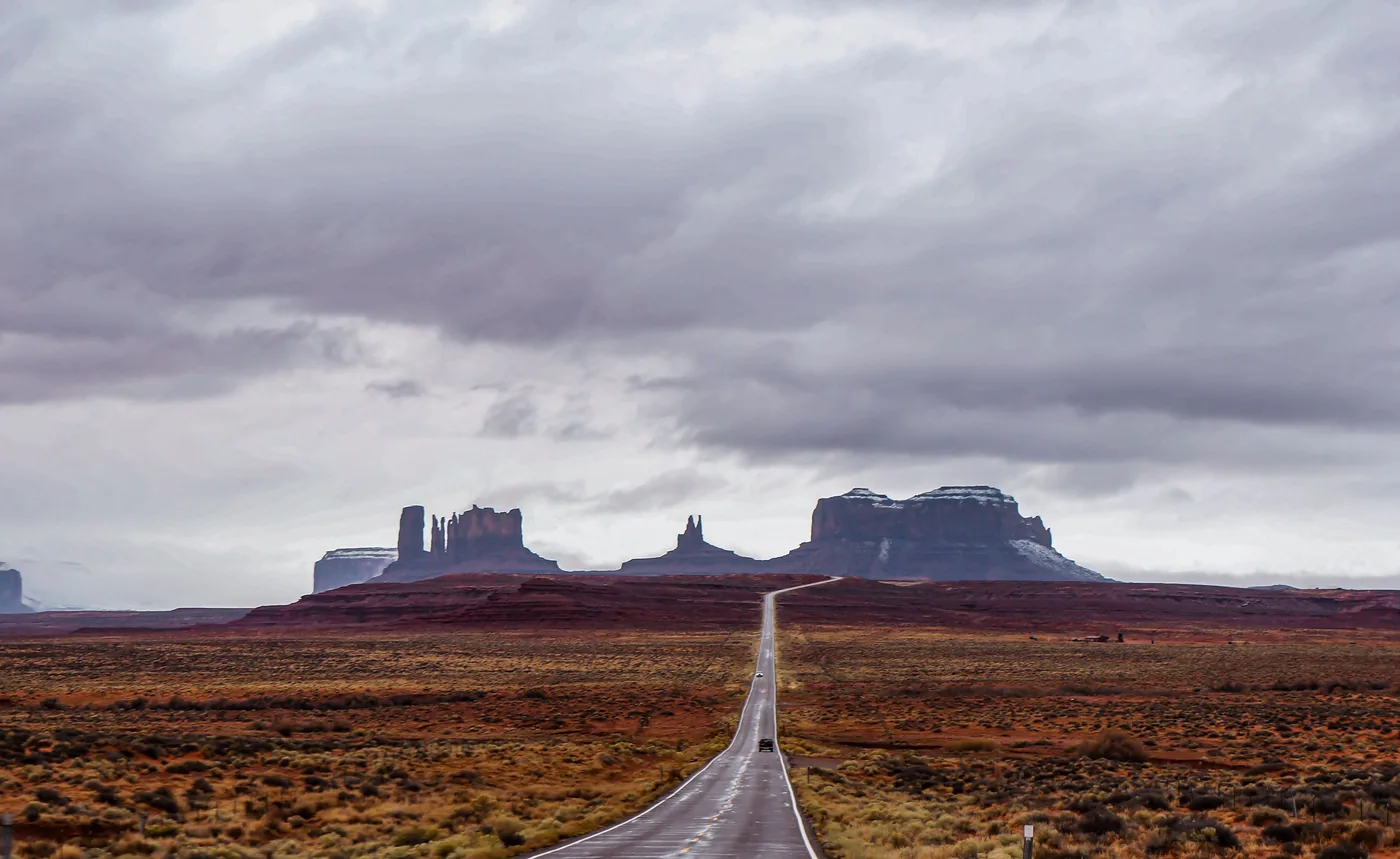 A scenic road leading toward Monument Valley under heavy cloud
